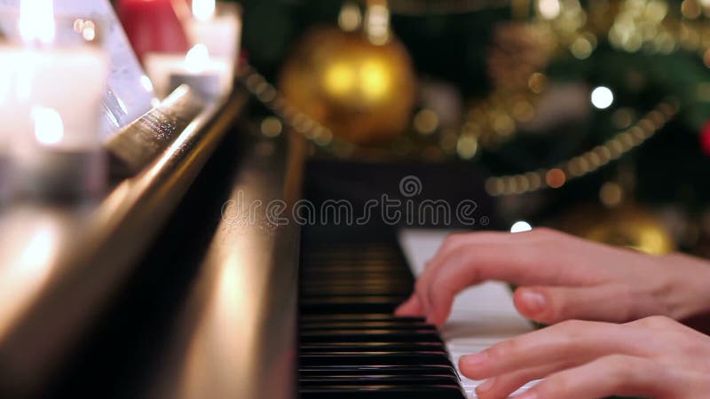 Menina que joga o piano perto da árvore de Natal