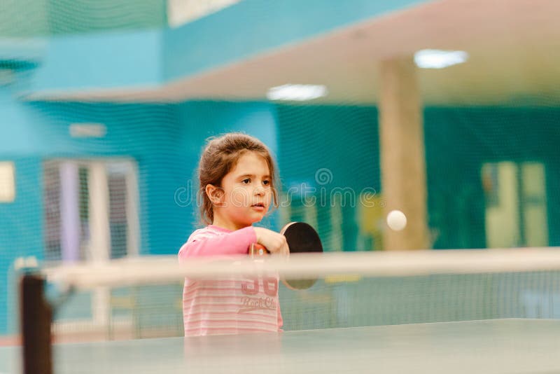 Menina que joga o tênis de mesa no salão do tênis, raquete de tênis que bate a bola fotos de stock royalty free Menina que joga o tênis de mesa no salão do tênis, raquete de tênis que bate a bola fotos de stock royalty free