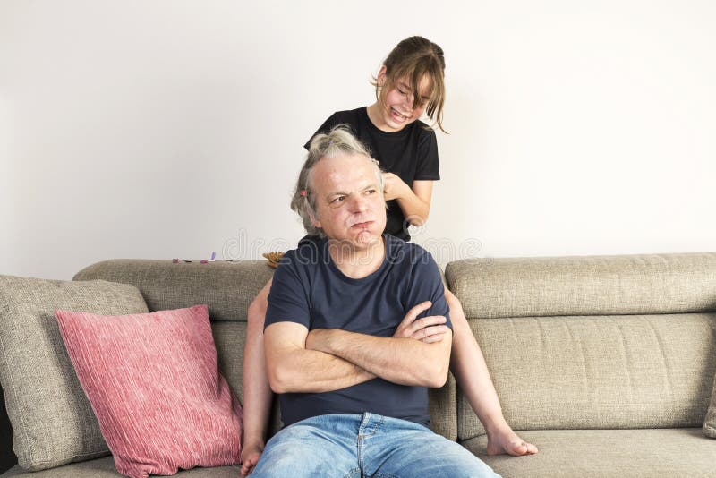 Menina que penteia e que faz a tranças seu paizinho em casa fotos de stock Menina que penteia e que faz a tranças seu paizinho em casa fotos de stock