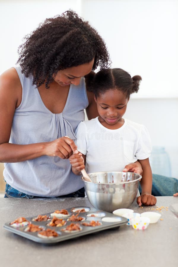 Adorable little girl preparing biscuits with her mother in the kitchen. Adorable little girl preparing biscuits with her mother in the kitchen