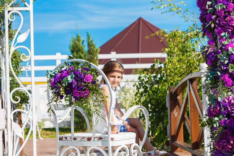 Menina que senta-se na cadeira sob o arco para a cerimônia de casamento decorado foto de stock Menina que senta-se na cadeira sob o arco para a cerimônia de casamento decorado foto de stock