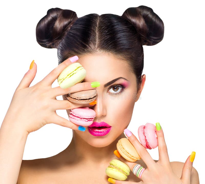 Menina que toma bolinhos de amêndoa coloridos fotos de stock