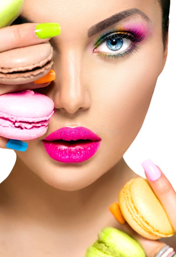 Menina que toma bolinhos de amêndoa coloridos fotografia de stock