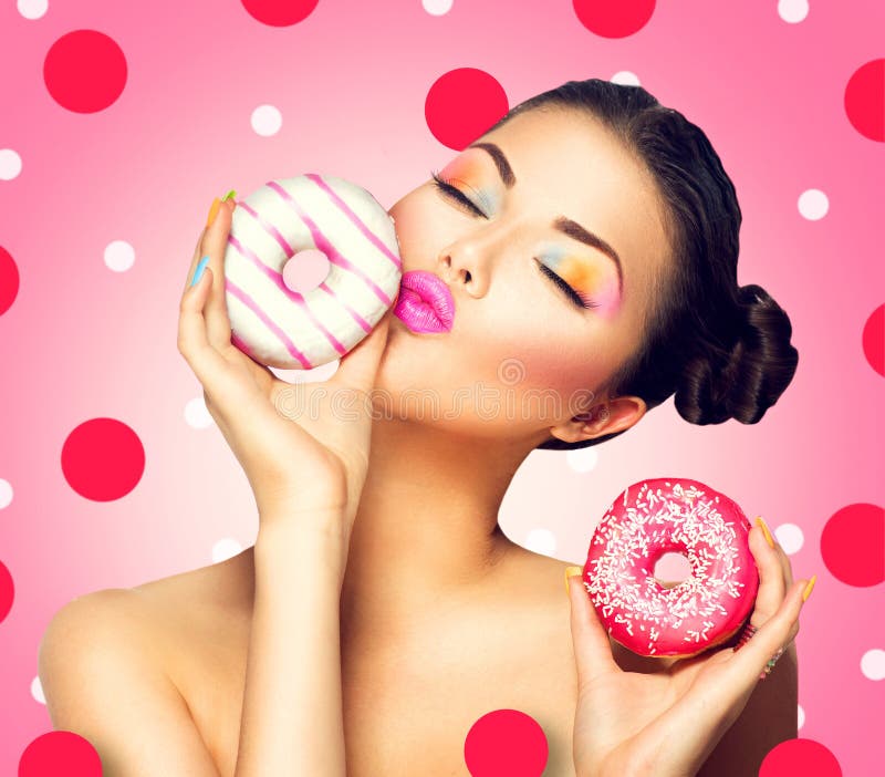 Rapariga a pegar em doces e donuts coloridos imagem de stock