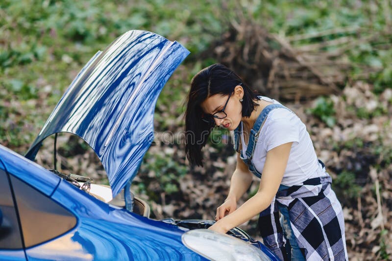 a menina repara o carro com uma capa aberta na estrada imagens de stock a menina repara o carro com uma capa aberta na estrada imagens de stock