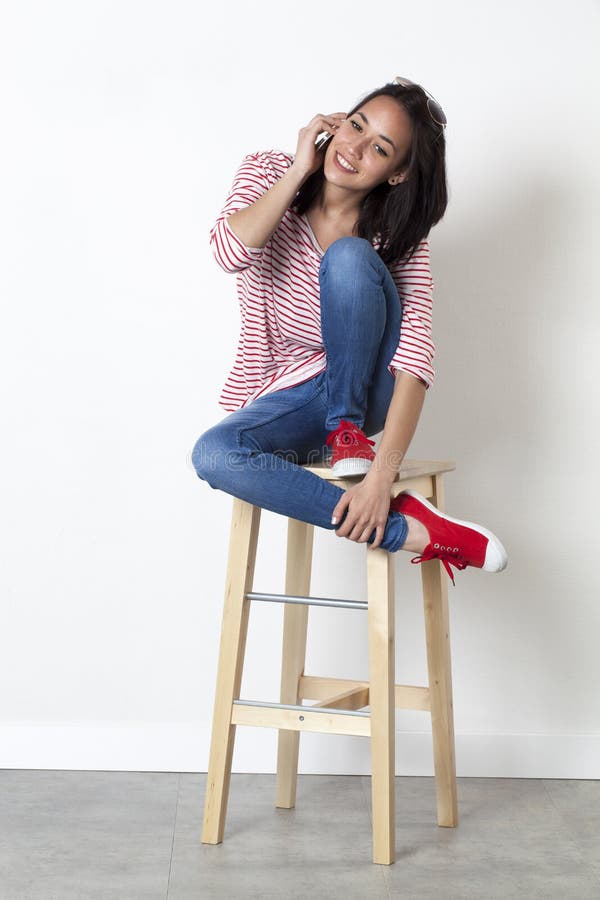Menina 20s multi-étnica relaxado que sorri em seu telefone celular foto de stock Menina 20s multi-étnica relaxado que sorri em seu telefone celular foto de stock