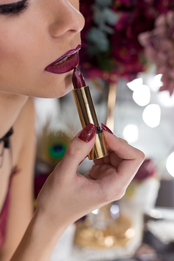 Menina 'sexy' elegante bonita com o Marsala brilhante da cor do batom do batom da composição na frente do espelho no vestuario fotos de stock Menina 'sexy' elegante bonita com o Marsala brilhante da cor do batom do batom da composição na frente do espelho no vestuario fotos de stock