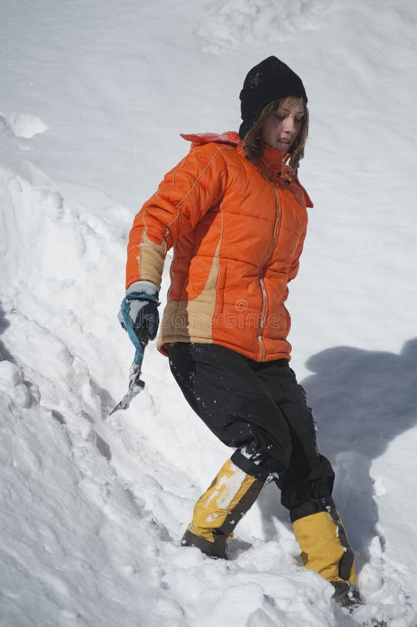 Menina sobe a montanha através da neve soprada pelo vento forte.