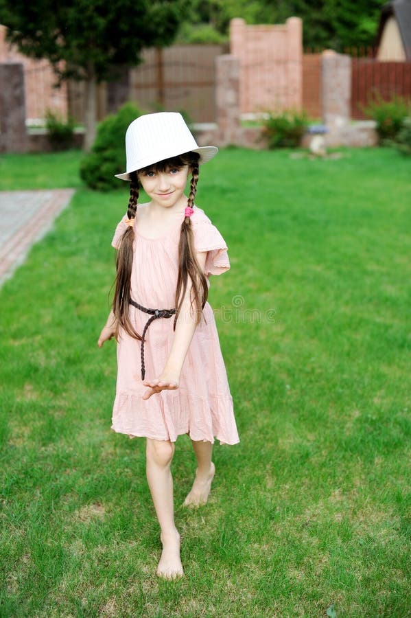 Menina surpreendente no vestido cor-de-rosa e no chapéu branco fotografia de stock Menina surpreendente no vestido cor-de-rosa e no chapéu branco fotografia de stock