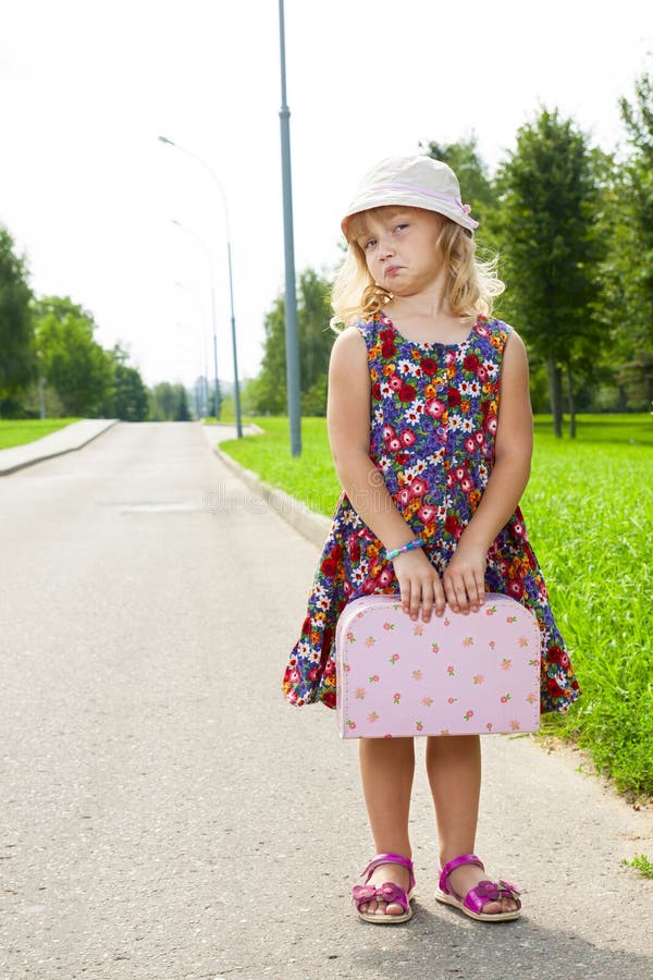 Menina com a mala de viagem que está na estrada imagem de stock Menina com a mala de viagem que está na estrada imagem de stock