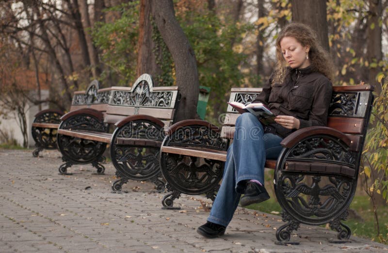 Menina só em uma leitura do parque fotos de stock
