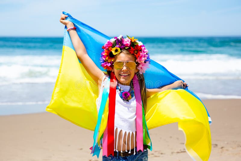 A menina ucraniana leva a bandeira azul e amarela de Ucrânia que vibra no fundo do céu azul e do mar fotos de stock A menina ucraniana leva a bandeira azul e amarela de Ucrânia que vibra no fundo do céu azul e do mar fotos de stock