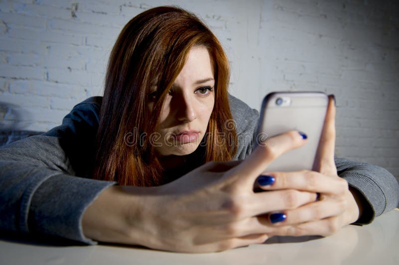Menina vulnerável triste nova que usa o abuso em linha do sofrimento assustado e desesperado do telefone celular que cyberbullyin fotografia de stock Menina vulnerável triste nova que usa o abuso em linha do sofrimento assustado e desesperado do telefone celular que cyberbullyin fotografia de stock