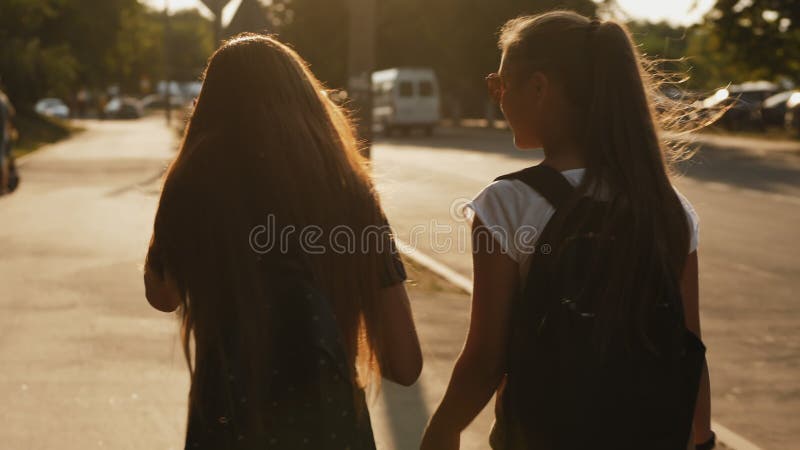 Meninas amigas andando juntas com mochilas e conversando