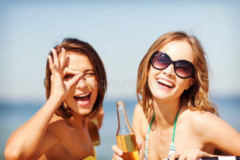 Meninas com bebidas nas cadeiras de praia imagem de stock Meninas com bebidas nas cadeiras de praia imagem de stock