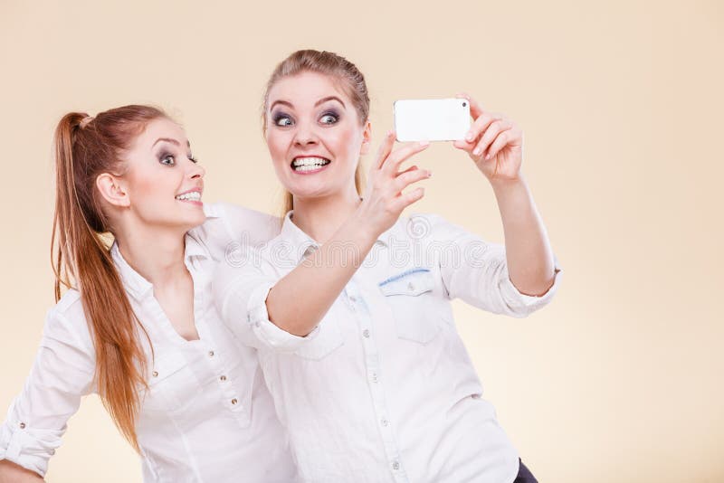 Meninas do estudante dos amigos que tomam a foto do auto com telefone esperto foto de stock Meninas do estudante dos amigos que tomam a foto do auto com telefone esperto foto de stock