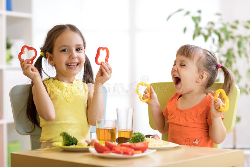 Meninas engraçadas das crianças que comem o alimento saudável Almoço das crianças em casa ou jardim de infância