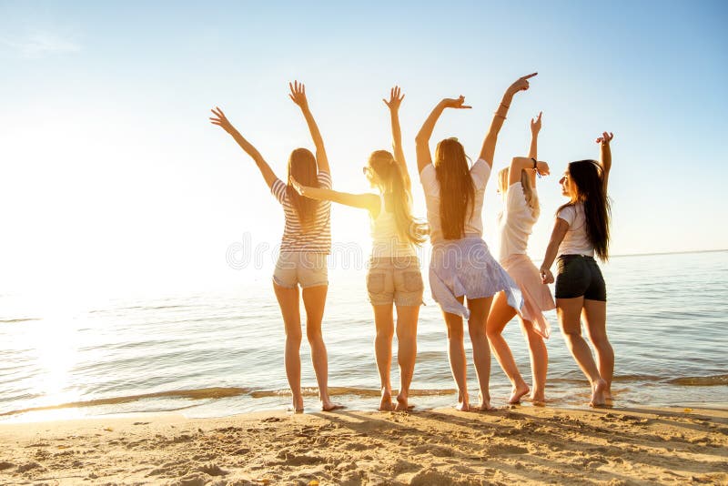 Meninas felizes com a praia aumentada do por do sol dos braços imagens de stock royalty free Meninas felizes com a praia aumentada do por do sol dos braços imagens de stock royalty free