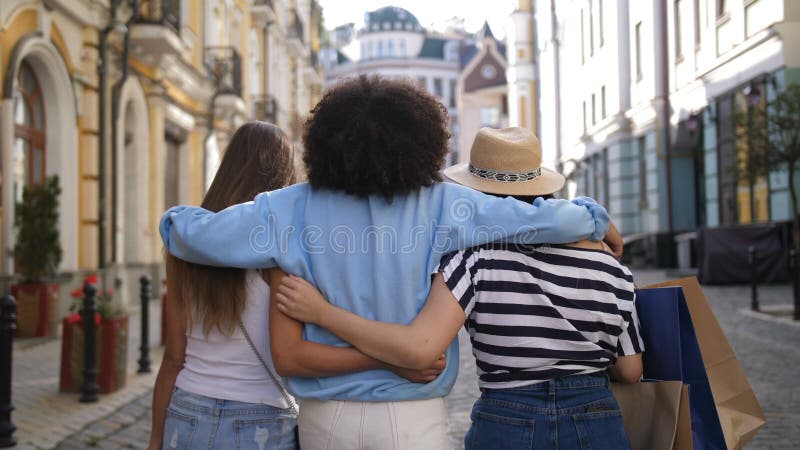 Meninas multirraciais que abraçam ao comprar