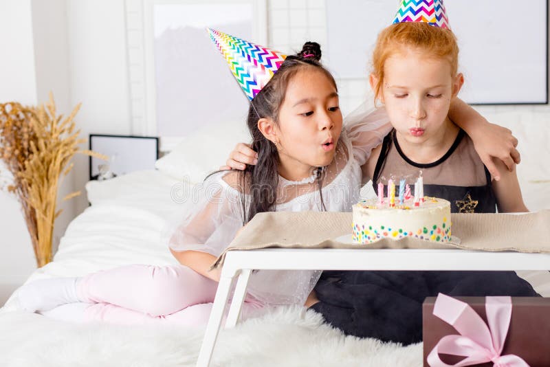 Meninas que fundem para fora velas no bolo de aniversário foto de stock royalty free Meninas que fundem para fora velas no bolo de aniversário foto de stock royalty free