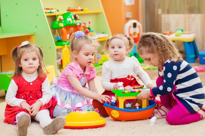 Três bonecas estão sentadas em carruagens de brinquedo rosa sala de jogos  no jardim de infância foto horizontal