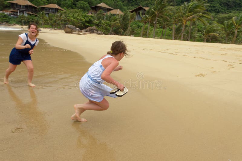 Meninas que riem e que jogam na praia fotografia de stock royalty free Meninas que riem e que jogam na praia fotografia de stock royalty free