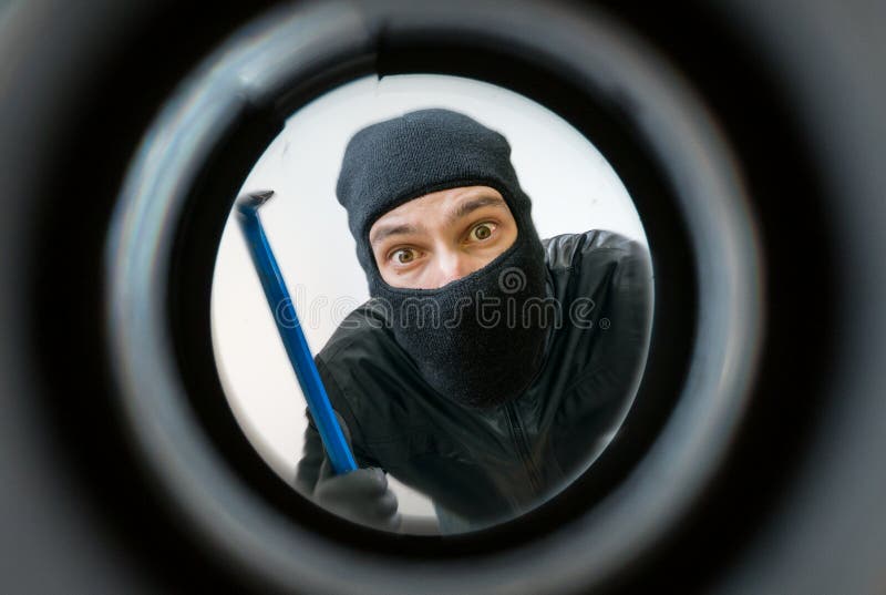 Mening door kijkglas Dief of de inbreker met balaclava wordt de gemaskeerd zijn achter de deur die royalty-vrije stock foto Mening door kijkglas Dief of de inbreker met balaclava wordt de gemaskeerd zijn achter de deur die royalty-vrije stock foto