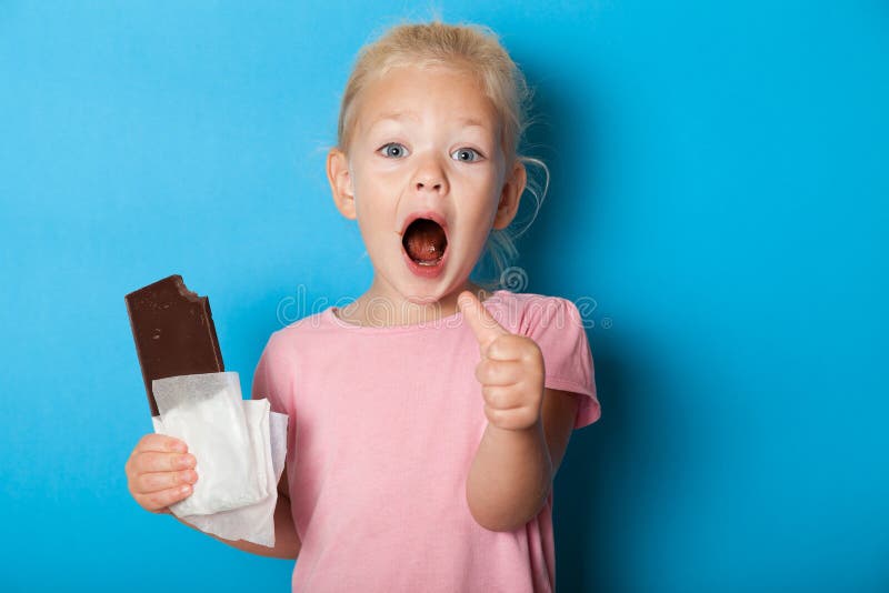 Menininha europeia come chocolate Conceito de gozação infantil foto de stock Menininha europeia come chocolate Conceito de gozação infantil foto de stock