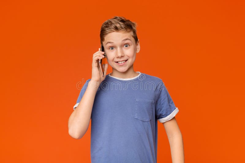Menino adolescente positivo que fala no telefone celular imagens de stock royalty free Menino adolescente positivo que fala no telefone celular imagens de stock royalty free