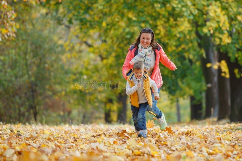 Menino adorável com sua mãe no parque do outono imagens de stock