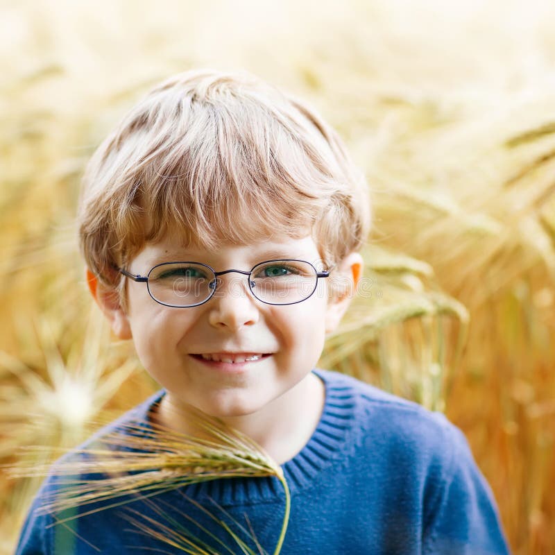 Adorable preschooler kid boy with glasses walking happily in wheat field on warm and sunny summer day. Adorable preschooler kid boy with glasses walking happily in wheat field on warm and sunny summer day