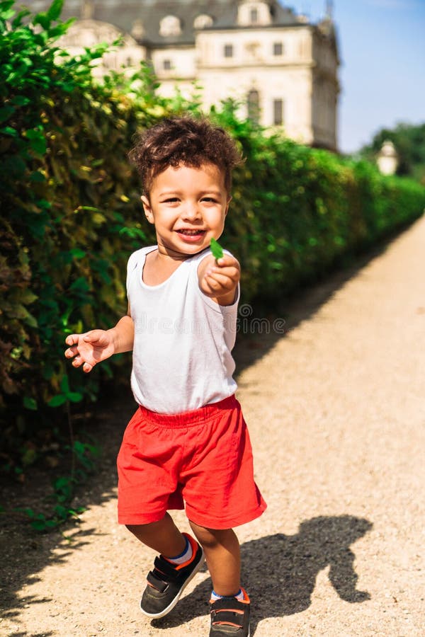 Menino afro-americano ou latino-americano pequeno bonito no short vermelho fotos de stock royalty free Menino afro-americano ou latino-americano pequeno bonito no short vermelho fotos de stock royalty free