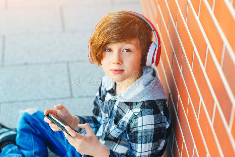 Menino bonito do ruivo com penteado à moda Menino de escola para escutar a música nos fones de ouvido Adolescente da forma na cam fotos de stock Menino bonito do ruivo com penteado à moda Menino de escola para escutar a música nos fones de ouvido Adolescente da forma na cam fotos de stock