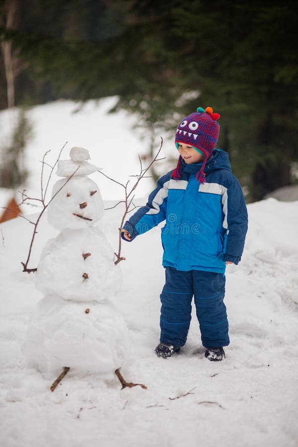 Menino bonito que faz o boneco de neve fotos de stock Menino bonito que faz o boneco de neve fotos de stock