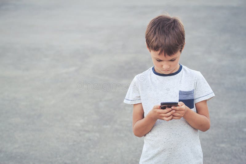 retrato menino jogando no celular enquanto espera por comida, garoto  sentado na cafeteria enviando texto para amigos, criança jogando jogo online  no celular. crianças com conceito de tecnologia 11248716 Foto de stock