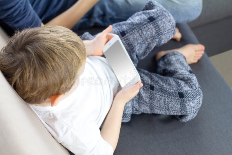 Menino da criança que usa o telefone celular Smartphone nas mãos da criança Criança que joga com telefone celular Crianças e disp imagens de stock Menino da criança que usa o telefone celular Smartphone nas mãos da criança Criança que joga com telefone celular Crianças e disp imagens de stock