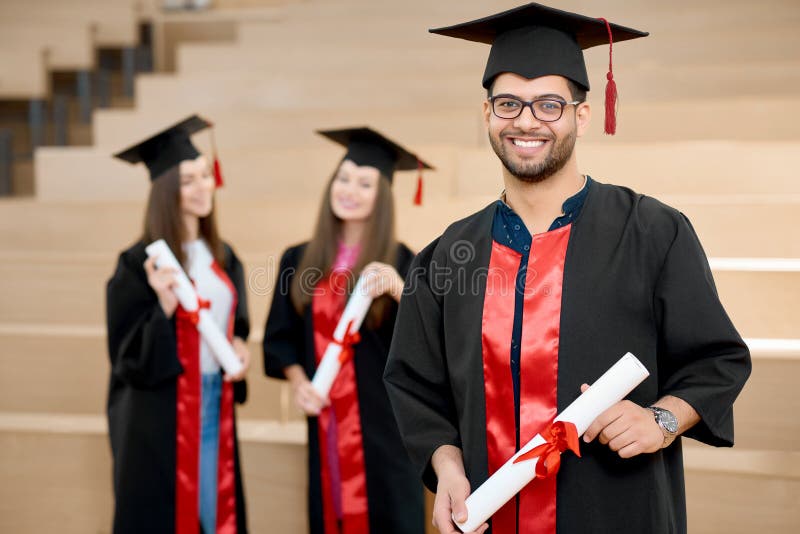 Menino de sorriso feliz que mantém o diploma da universidade fotografia de stock royalty free Menino de sorriso feliz que mantém o diploma da universidade fotografia de stock royalty free