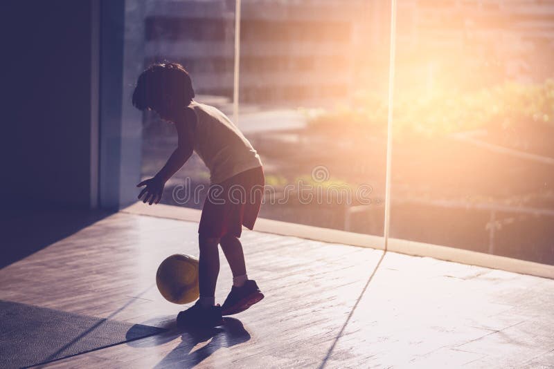 O Menino Do Jogador De Futebol Está Pisando Na Bola Na Sala Foto