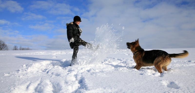 Menino e cão que jogam na neve