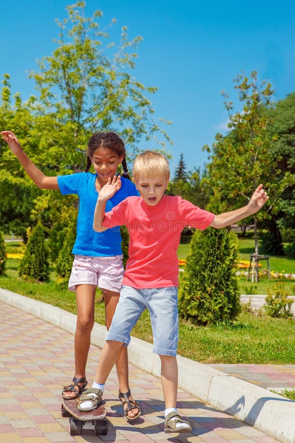 Rapaz e rapariga na mesma skateboard imagens de stock