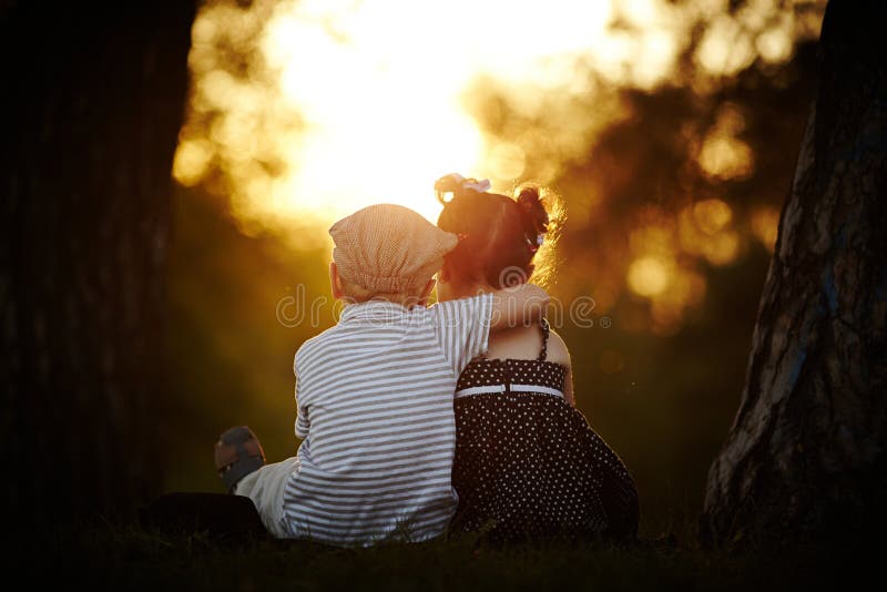 Menino e menina no por do sol foto de stock royalty free Menino e menina no por do sol foto de stock royalty free