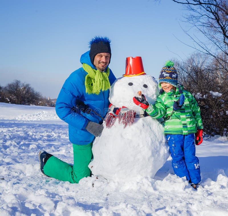 Menino e seu pai com um boneco de neve foto de stock