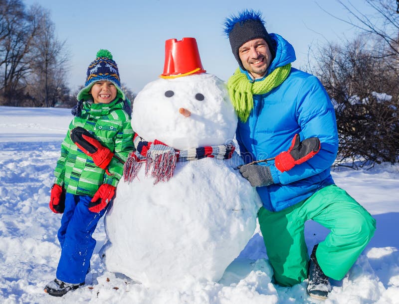 Menino e seu pai com um boneco de neve fotos de stock