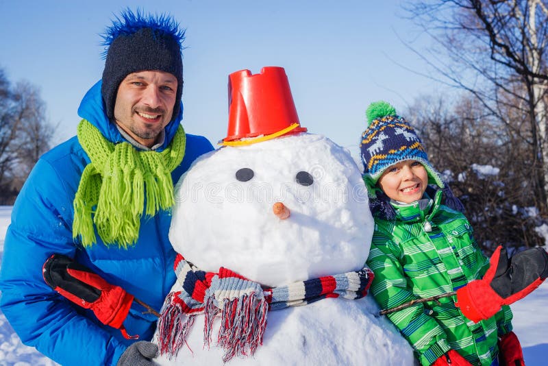 Menino e seu pai com um boneco de neve fotos de stock royalty free