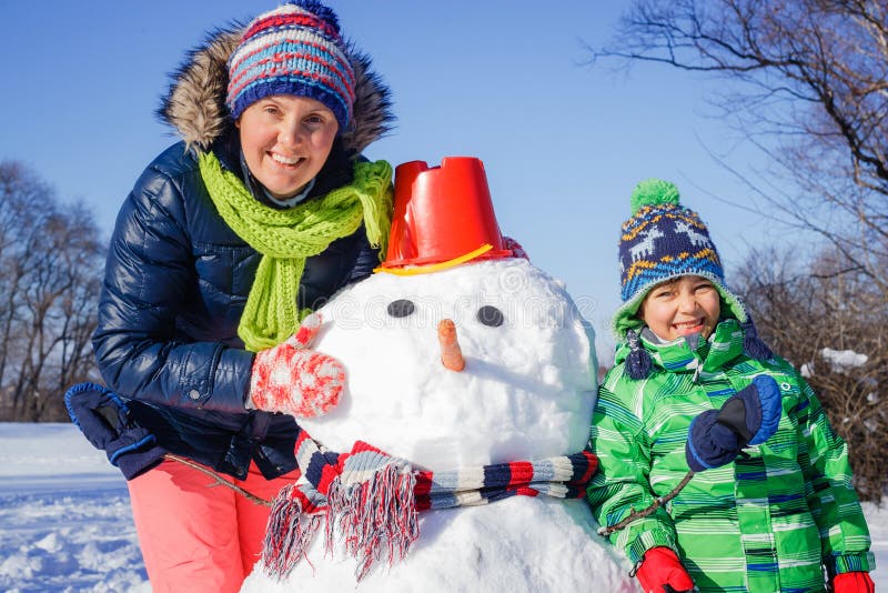 Menino e sua mãe com um boneco de neve fotos de stock royalty free