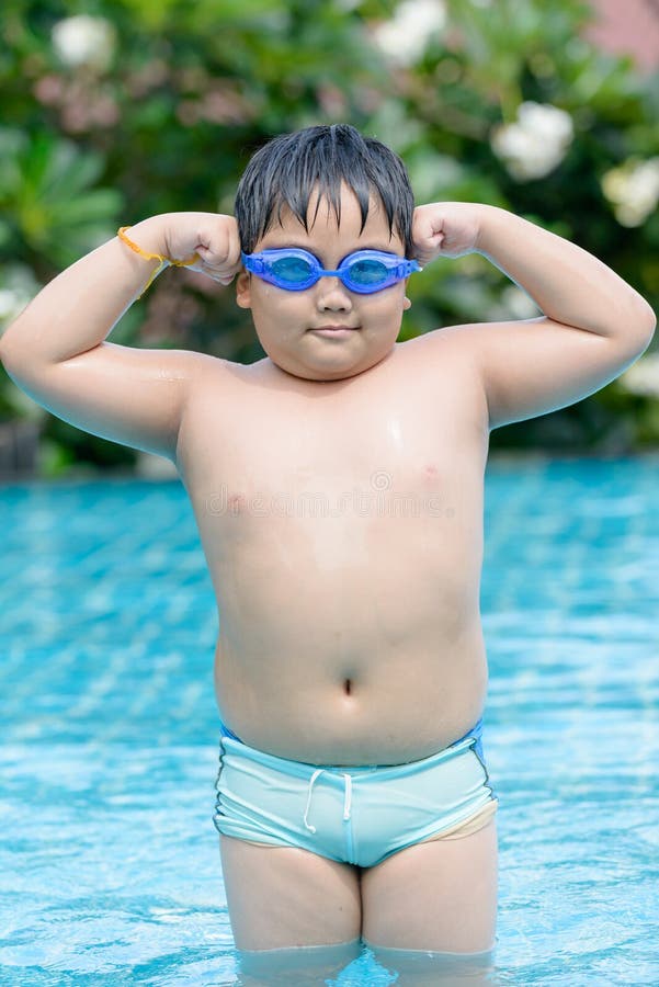 Menino gordo asiático que mostra lhe o músculo fotografia de stock Menino gordo asiático que mostra lhe o músculo fotografia de stock