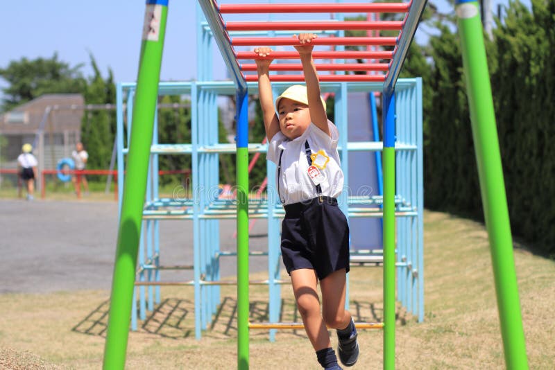 Menino japonês que joga com as barras de macaco fotografia de stock Menino japonês que joga com as barras de macaco fotografia de stock