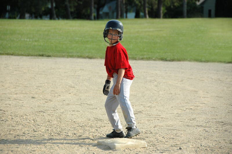 Menino na base no jogo de basebol foto de stock Menino na base no jogo de basebol foto de stock