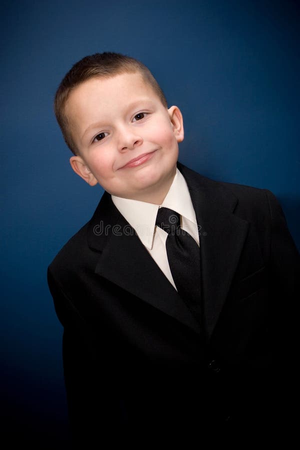 Young boy wearing a suit smiling in front of a blue backdrop. Young boy wearing a suit smiling in front of a blue backdrop.