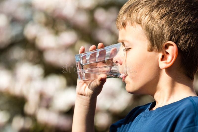 Menino que bebe a água pura do vidro